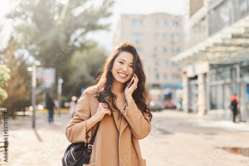 Lifestyle portrait happy Asian kazakh woman talking on mobile phone and laughing