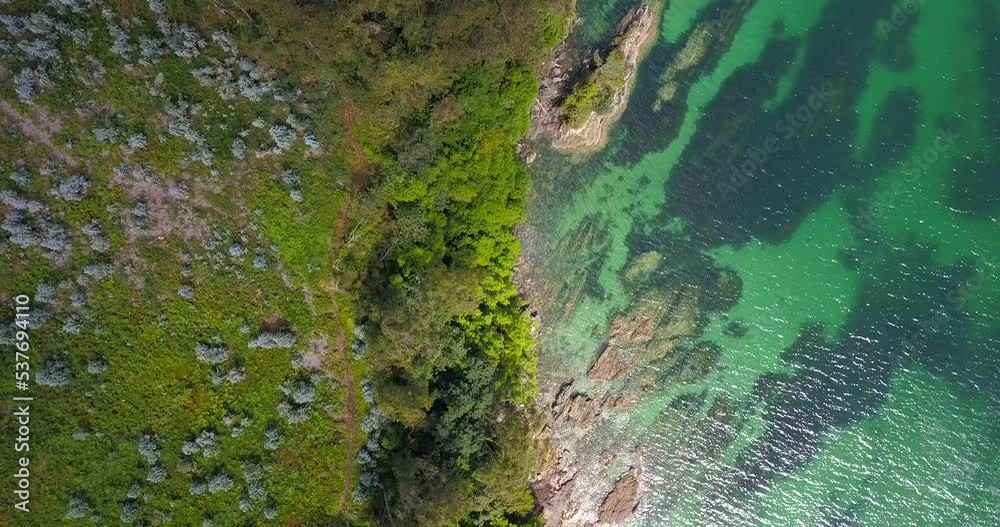 Aerial Birds Eye View Of Galicia Coastline Next To Green Turquoise Waters Shimmering In Sunlight. Pedestal Up Aerial Birds Eye View Of Galicia Coastline Next To Green Turquoise Waters Shimmering In Sunlight. Pedestal Up