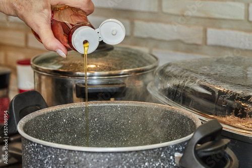 Pours maple syrup into the pot with the dish being prepared