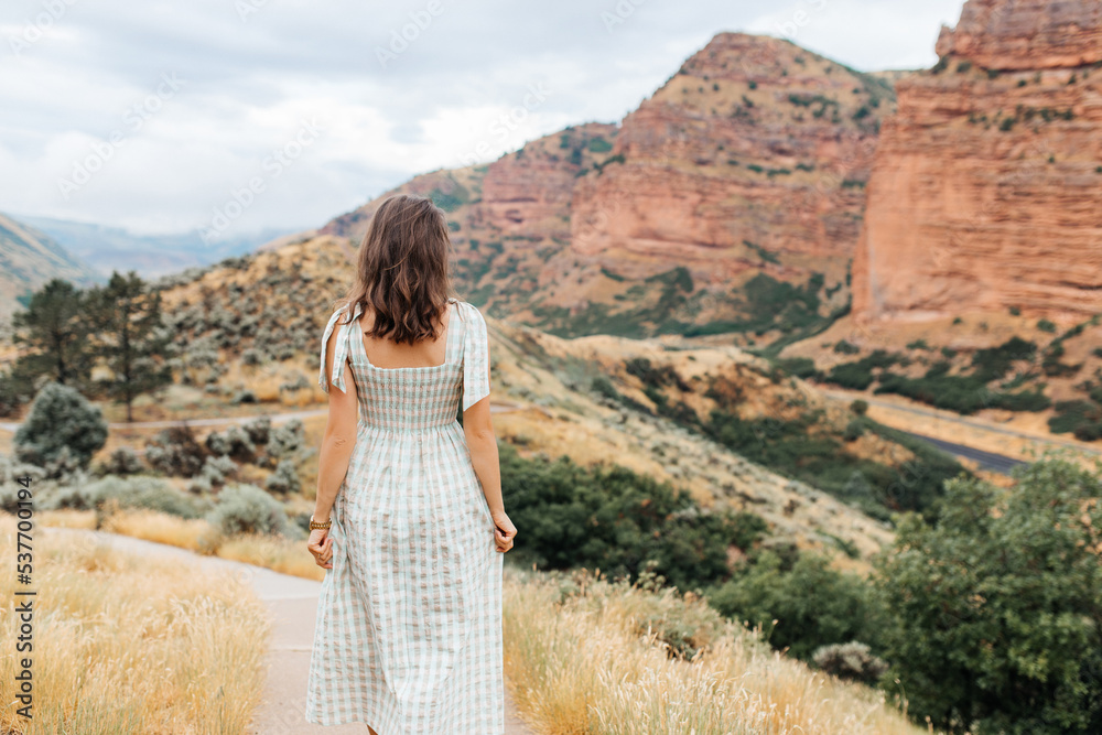 A young girl walks among the red high mountains. A girl walks in autumn among the beautiful mountains of Utah,USA