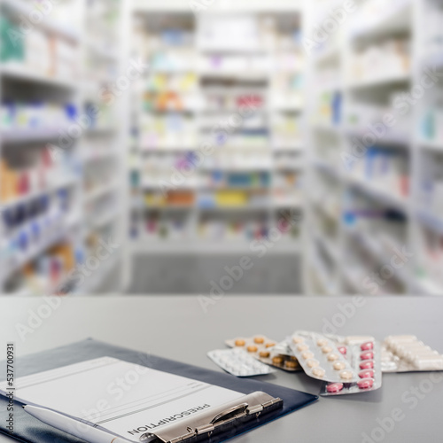 Drug prescription and pills in blister lying on table on pharmacy background