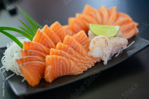 Salmon Sashimi in Japanese buffet restaurant menu. Fresh salmon fillet on black plate salmon slices. Salmon sashimi. Asian Food Menu. Seafood sashimi.