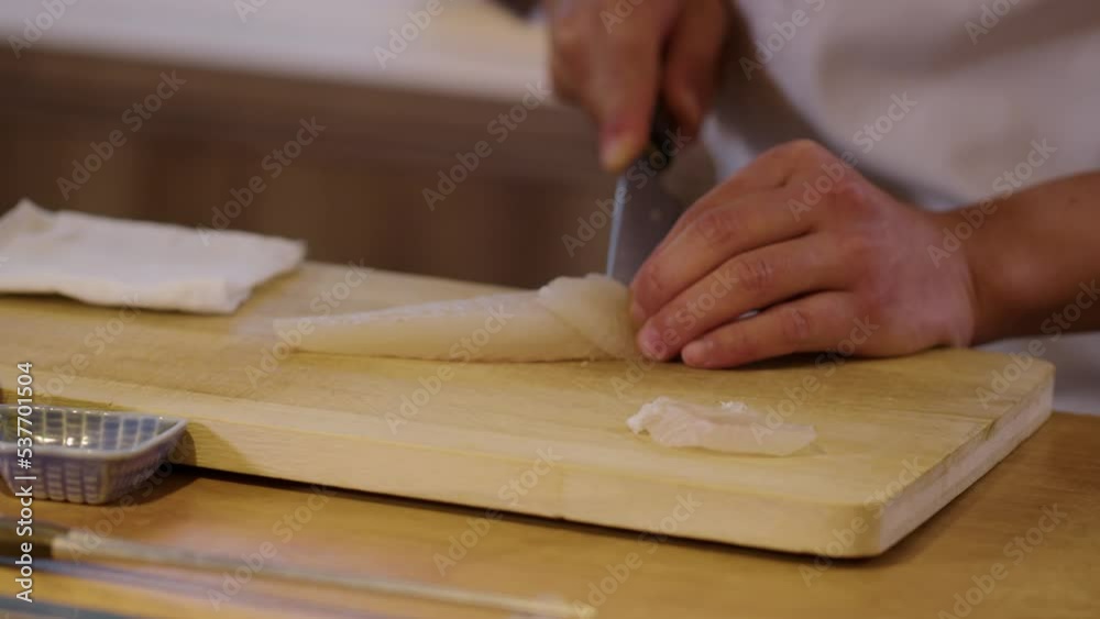 White fish being sliced for sashimi by professional Japanese chef; close-up White fish being sliced for sashimi by professional Japanese chef; close-up