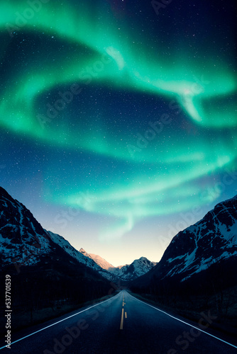 Northern lights aka aurora borealis above a road and mountains in Norway