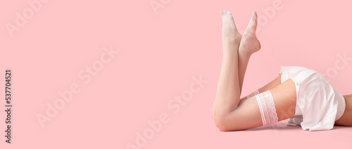 Legs of beautiful young woman in white stockings on pink background with space for text