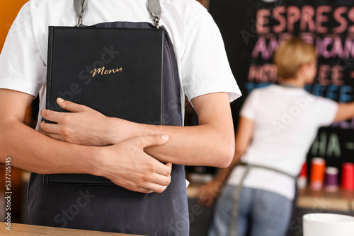Young male barista with menu in cafe, closeup