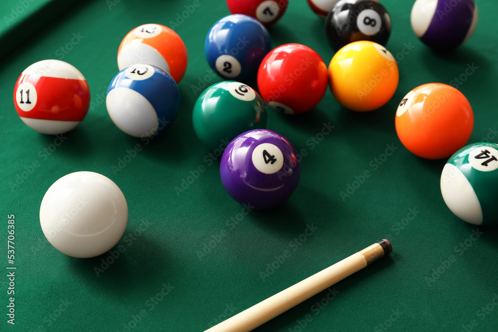 Colorful billiard balls with cue on table, closeup Colorful billiard balls with cue on table, closeup