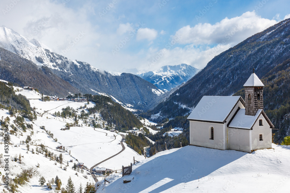 Chapel on a hill in a snowy alp valley