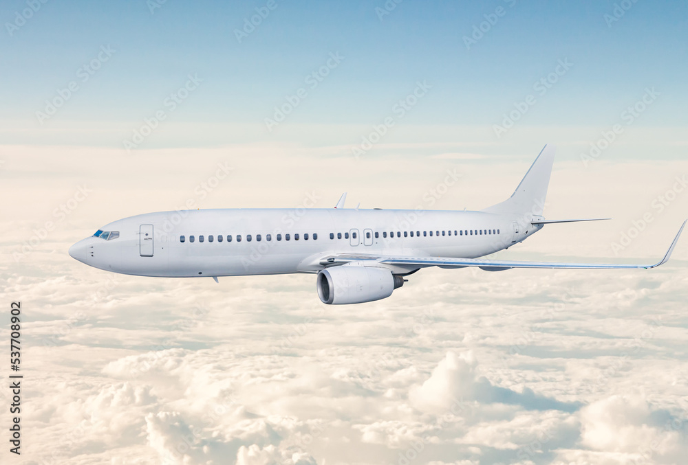 White passenger jet plane fly in the air above the clouds