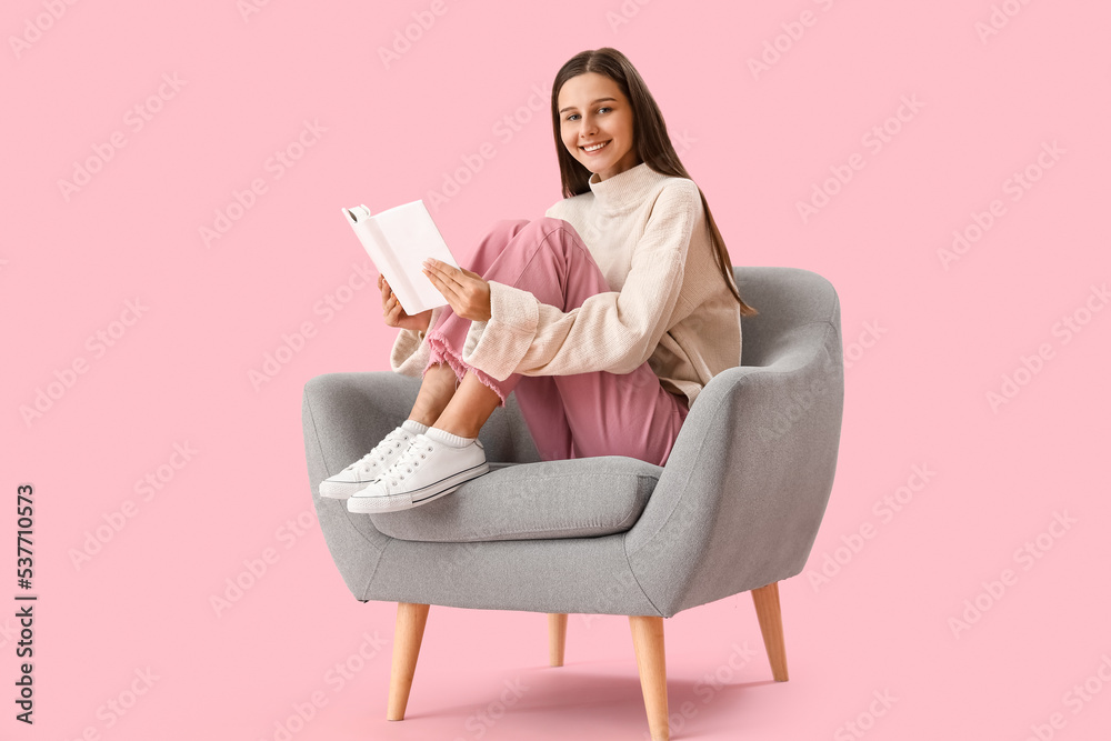 Beautiful woman with book sitting in armchair on pink background Beautiful woman with book sitting in armchair on pink background