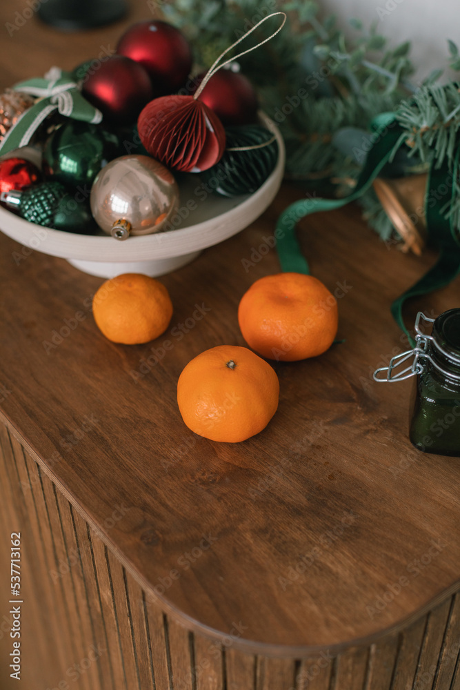 Tangerines, Christmas decor, wreath on wooden dresser. Modern home holiday decorations.