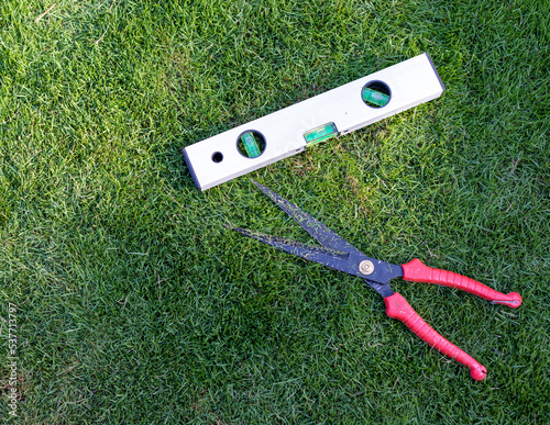 Spirit level tool and hedge trimmer in the grass