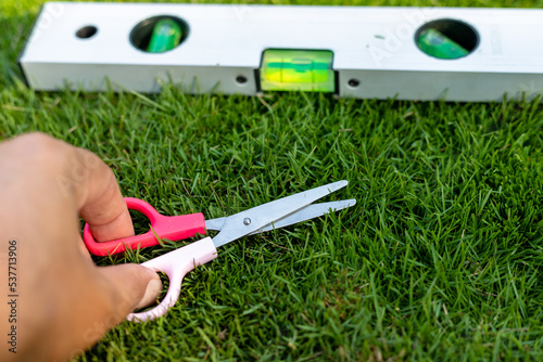 The hand mower cutting the grass using scissors and leveling tool