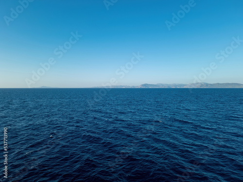 Sea dark blue ripple water meets clear blue sky background. Greek island, Cyclades, Greece. Space