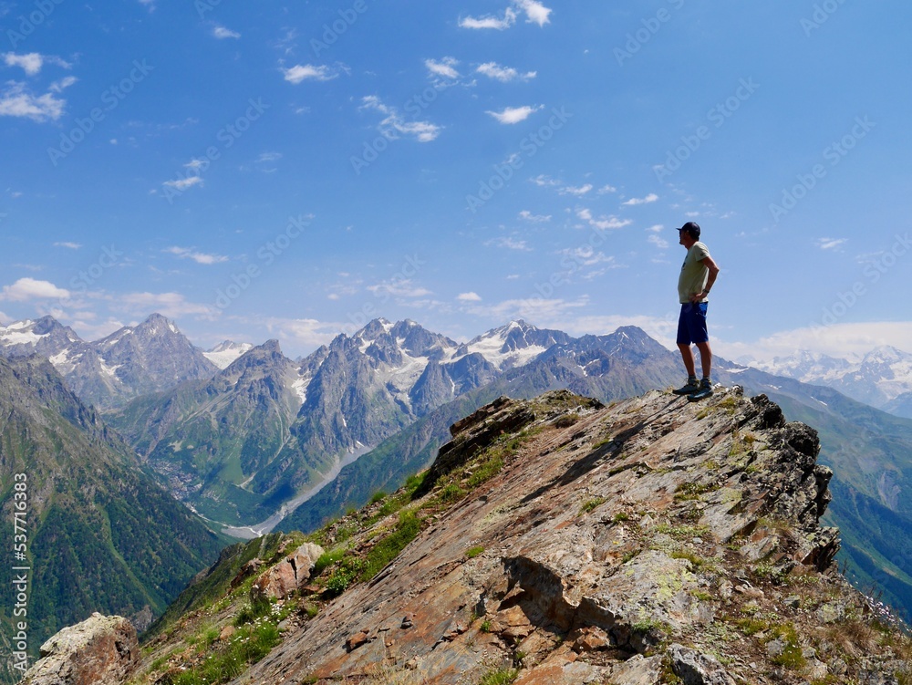 Man hiking at Koruldi lakes. Hiker enjoying beautiful view of Great Caucasus mountains close to Mestia in Upper Svaneti, Georgia. Man hiking at Koruldi lakes. Hiker enjoying beautiful view of Great Caucasus mountains close to Mestia in Upper Svaneti, Georgia.