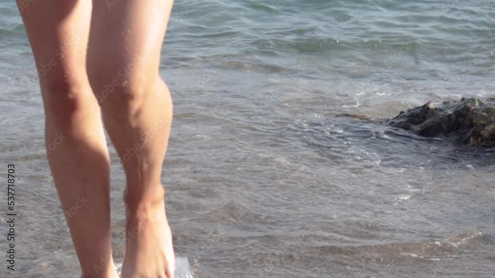 sexy slim attractive woman in swimsuit lying in water sea waves on sands beach.girl feet legs barefoot runing in ocean or walking from water on beach.summer sea vacation leisure time warm weather.back sexy slim attractive woman in swimsuit lying in water sea waves on sands beach.girl feet legs barefoot runing in ocean or walking from water on beach.summer sea vacation leisure time warm weather.back