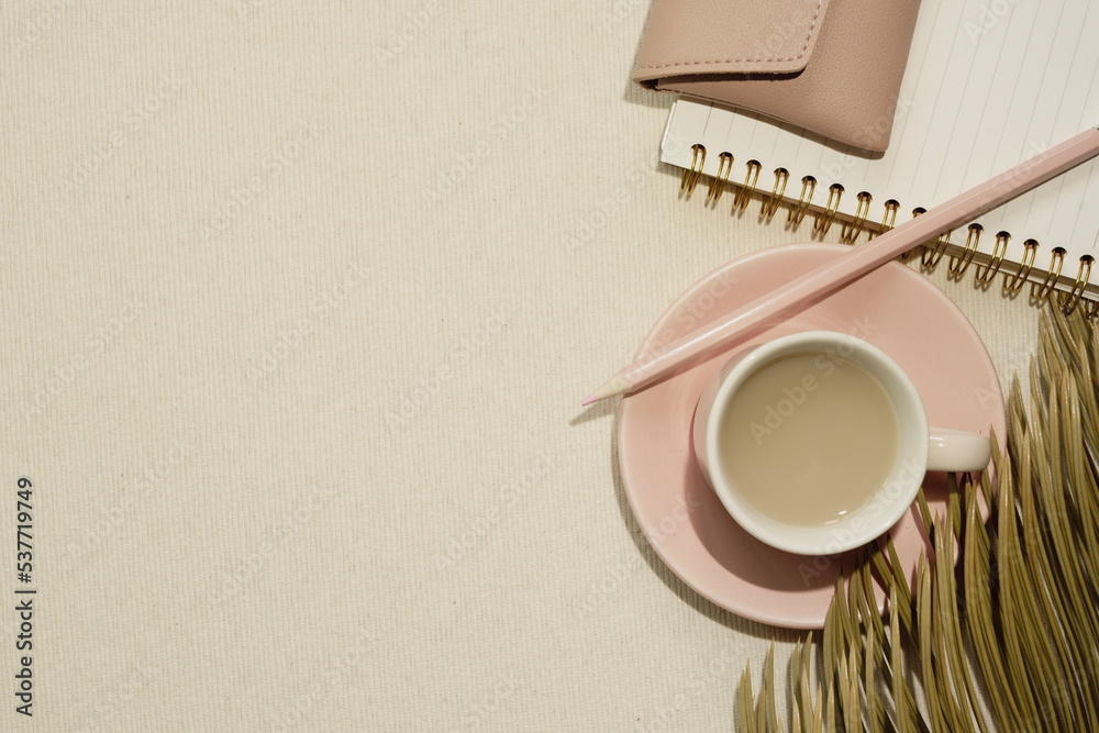 Pink supplies. Cup of coffee and notebook, colored pencil, pouch on beige fabric background. flat lay, top view, copy space