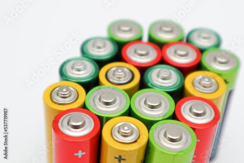 Different colours of batteries on white background. Close up of positive ends batteries, selective focus. Used battery for recycling. Hazardous garbage concept
