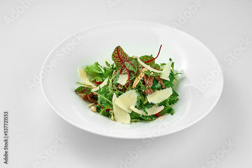 Salad with roast beef and parmesan on a white plate. Close-up. Selective focus