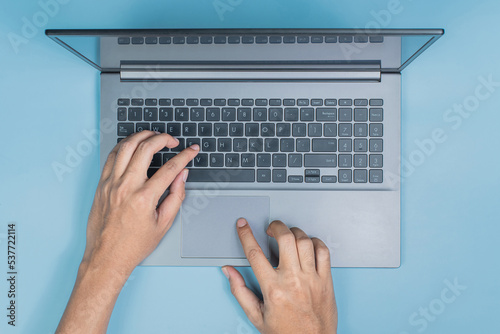 Top view hand of business man working at loptop computer in office on blue table