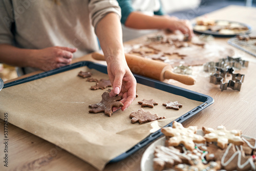 Detail of caucasian woman putting raw gingerbread cookies on baking tray