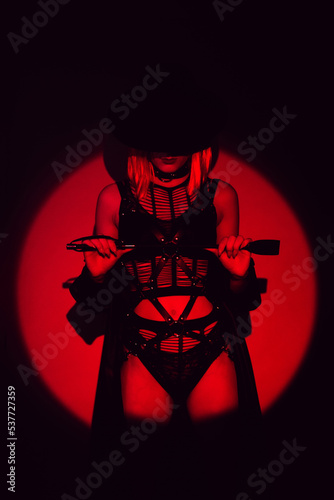 sexy girl with a leather whip in underwear and a hat. BDSM concept of a dominant woman