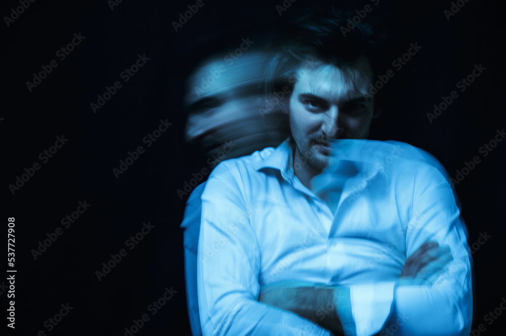 schizophrenic portrait of psychopathic man with mental disorders in white shirt on dark background