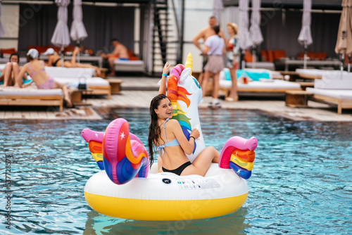 Woman on inflatable unicorn toy mattress float in pool. © teksomolika