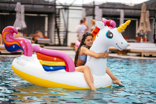 Woman on inflatable unicorn toy mattress float in pool.