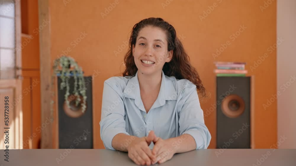 Young woman speaking to camera during video conference call or remote chat. Working from home or hosting a conversation over the web. Dressed professionally smiling and enjoying talking to camera 