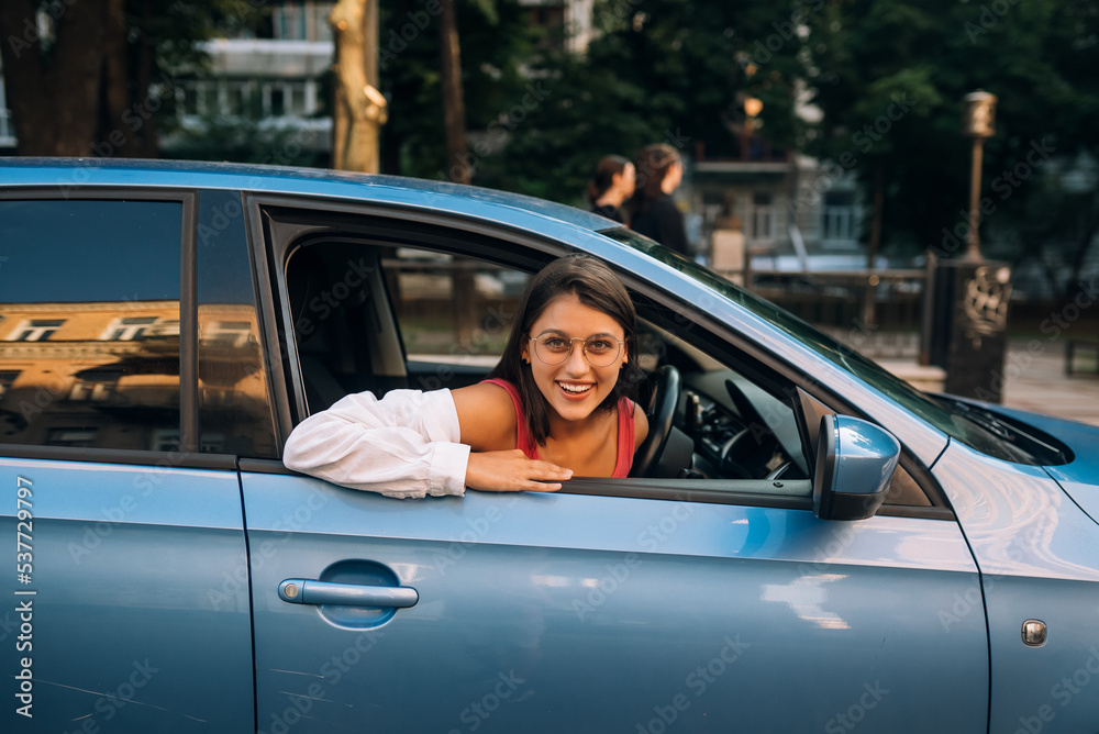 Happy woman in a car, looking out of the window.