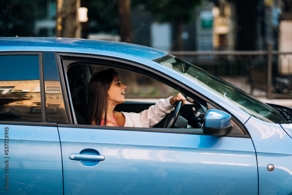 Woman sitting in car and using her smartphone.