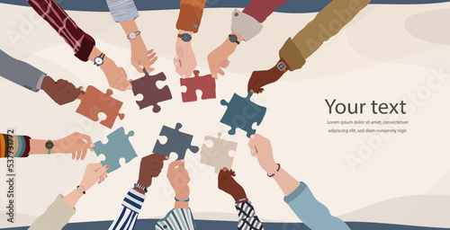 Group of multicultural business people with raised arms holding a piece of jigsaw. Colleagues of diverse ethnic groups and cultures. collaborate- Cooperate. Concept of teamwork.Copy space