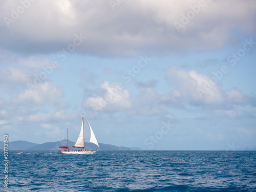 Distant sailboat against blue sky with white clouds © Katherine Rock