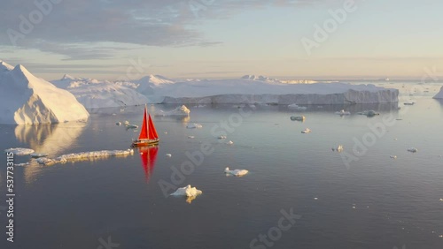Sail boat cruising among ice bergs during dusk, Disko Bay, Greenland.
Midnight sun, romantic view.
Climate change and global warming
