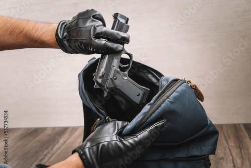 Принти на полотні man in gloves takes a gun out of his backpack