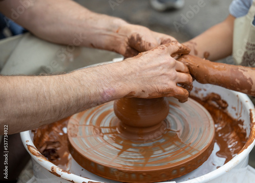 Potters and child hands. The potter teaches a young student.
