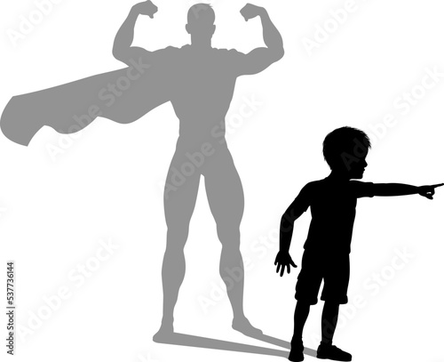 A superhero child or kid boy revealed by his shadow silhouette as a super hero in a cape.