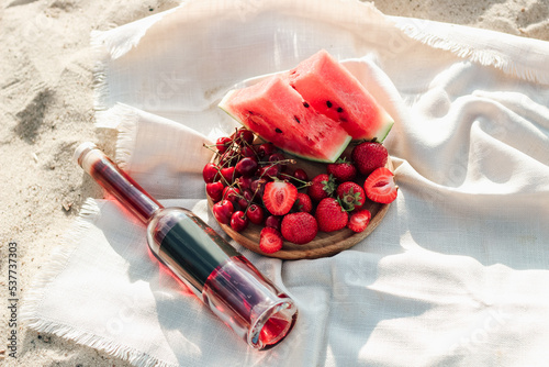 Champagne with a tray of fruits, strawberries and cherries on a picnic.
