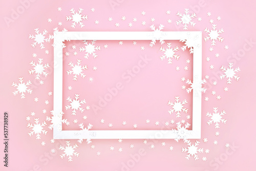 Festive Christmas and New Year snowflake background border on pastel pink with white frame and traditional ornate decorations. Minimal composition for the winter holiday season. 
