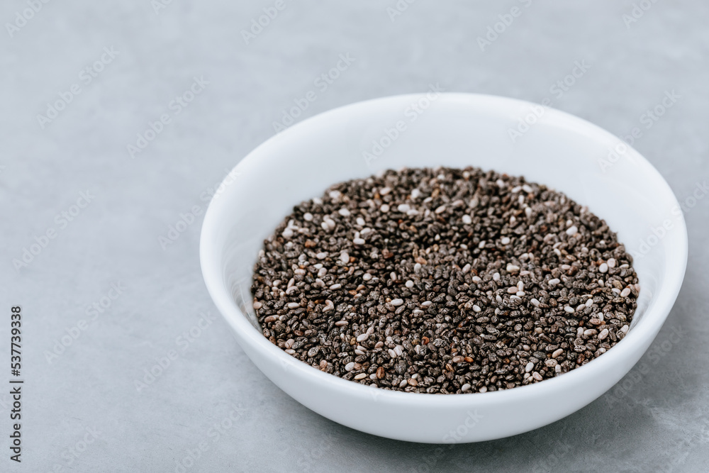 Chia seeds. Organic Dry Black and White Chia Seeds in bowl on gray stone background Chia seeds. Organic Dry Black and White Chia Seeds in bowl on gray stone background