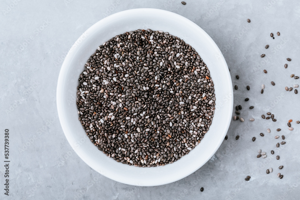 Chia seeds. Organic Dry Black and White Chia Seeds in bowl on gray stone background. Chia seeds. Organic Dry Black and White Chia Seeds in bowl on gray stone background.