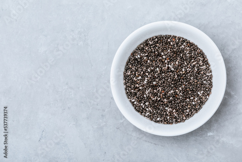 Chia seeds. Organic Dry Black and White Chia Seeds in bowl on gray stone background.