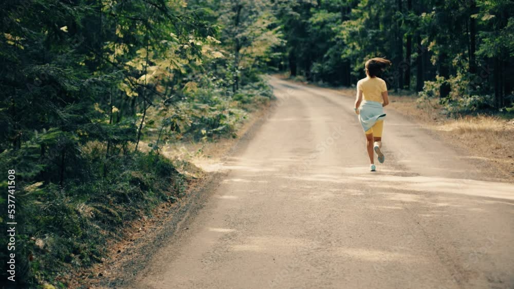 Active young adult woman training in the forest. The fitness female is jogging outdoor. Concept of workouts running and healthy lifestyle. Yellow and green. Active young adult woman training in the forest. The fitness female is jogging outdoor. Concept of workouts running and healthy lifestyle. Yellow and green.