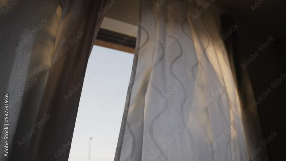 Open window or glass door to porch or deck with curtain blowing in the ...