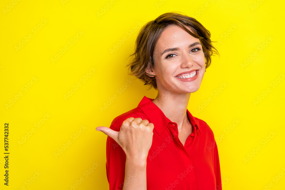 Portrait of gorgeous nice lovely positive girl with bob hairdo dressed red shirt directing empty space isolated on yellow color background