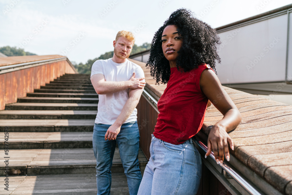 Serious diverse couple standing on stairs outside Serious diverse couple standing on stairs outside