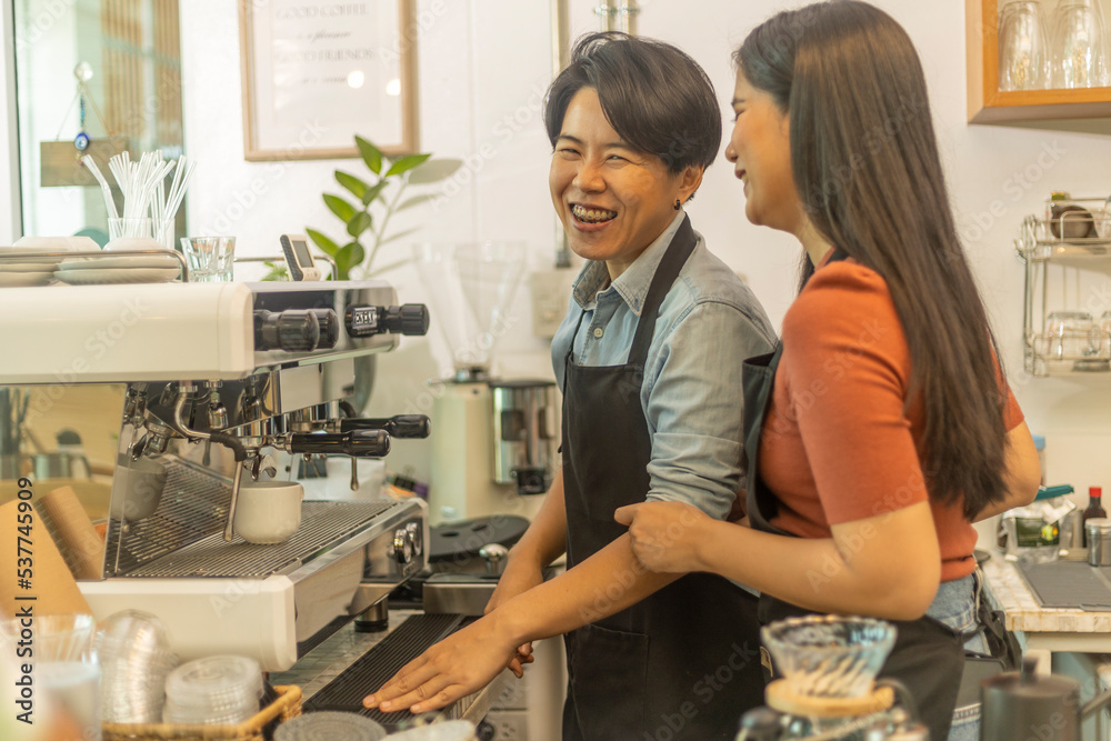 Obraz premium Female business owner works with her LGBT partner to prepare coffee or drink for customer in a coffee shop. A couple of LGBT startup help each other at a coffee counter for their business.
