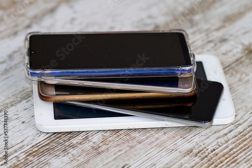 A battery of mobile phones and tablets with their headphones and charger
