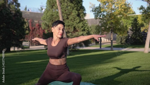 Attractive mature woman doing fitness and yoga outdoors. Active sports woman over 60 years old
